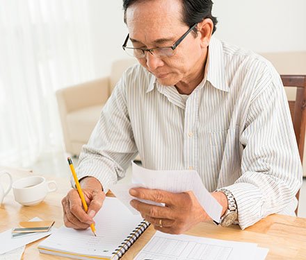 Senior man writing at desk