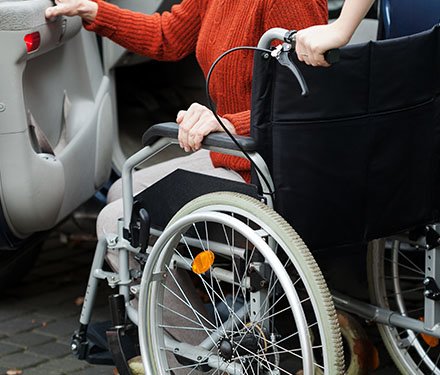 Woman in a wheelchair getting into a car